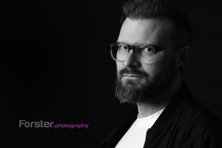 junger Mann mit Brille und Bart beim Bewerbungs-Fotoshooting