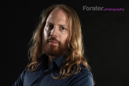 Junger Mann mit langen Haaren lächelt in die Kamera beim Fotoshooting in Iserlohn