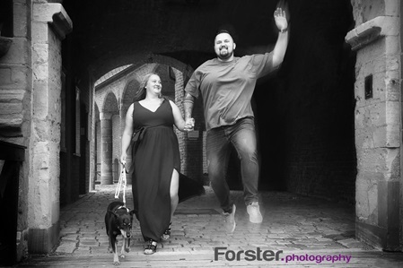 Junges Paar hüpft durch ein Burgtor beim Fotoshooting in Iserlohn