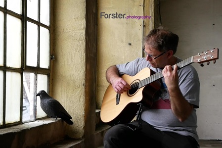 Mann spielt Gitarre am Fenster in einer alten Fabrikhalle