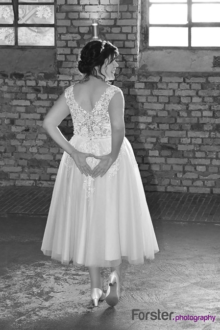 Braut im Hochzeitskleid vor einem Fenster beim Brautpaar-Fotoshooting
