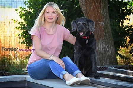 Eine junge Frau sitzt mit großem Hund am Pool.