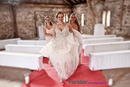 Eine Braut im weißen Hochzeitskleid läuft gemeinsam mit ihren Brautjungfern über den roten Teppich beim Fotoshooting