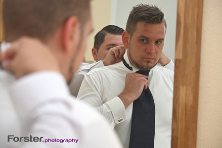Bräutigam steht vor der Hochzeit mit seinem Trauzeugen beim getting ready Fotoshooting vor dem Spiegel
