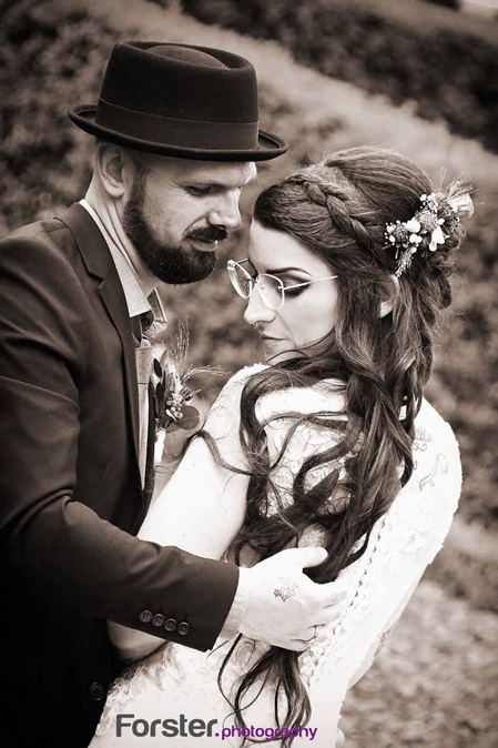 Ein Brautpaar im Hochzeits-Outfit steht beim Fotoshooting dicht zusammen