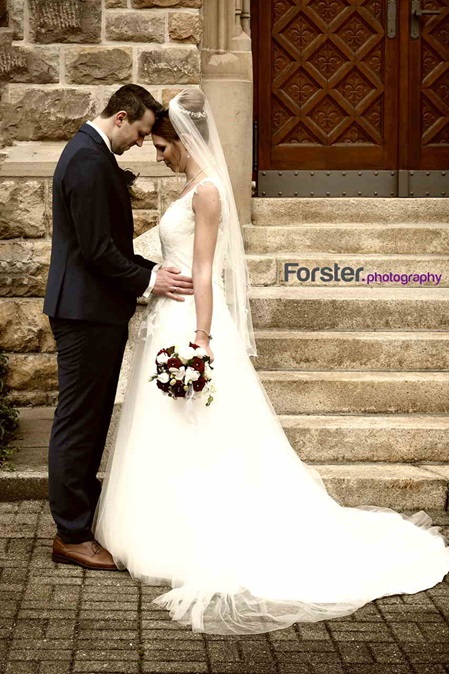 Ein Brautpaar steht beim Hochzeits-Fotoshooting dicht zusammen Stirn an Stirn vor einer Steintreppe