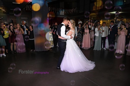 Ein Brautpaar tanzt auf der Hochzeit seinen Eröffnungstanz vor vielen Gästen mit bunten Lichtern
