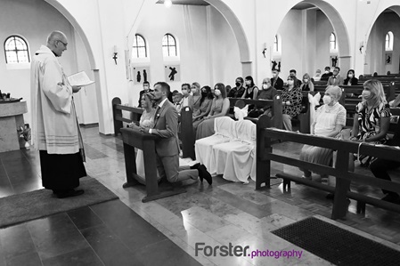 Ein Brautpaar kniet an der Hochzeit in der Kirche am Altar vor dem Pastor und blickt gemeinsam nach vorne