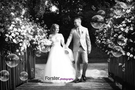 Ein Brautpaar im Hochzeits-Outfit beim Fotoshooting geht Hand in Hand und schaut sich verliebt an