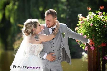 Ein Brautpaar im Hochzeits-Outfit beim Fotoshooting schaut sich verliebt und glücklich an