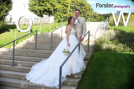 Ein Hochzeitspaar steht beim Fotoshooting auf einer Treppe im Sauerlandpark Hemer und blickt glücklich zur Kamera