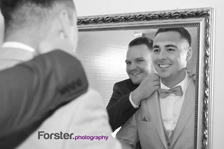 Bräutigam steht vor der Hochzeit mit seinem Trauzeugen beim getting ready Fotoshooting vor dem Spiegel