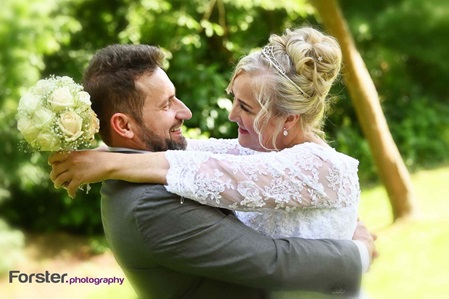 Brautpaar umarmt sich beim Fotoshooting und schaut sich am Hochzeitstag dabei verliebt an