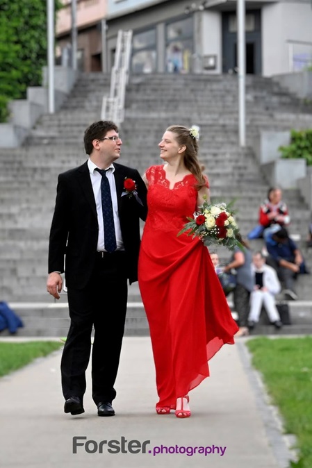 Brautpaar beim Fotoshooting nach der Trauung laufen auf die Kamera zu. Die Braut trägt ein rotes Kleid