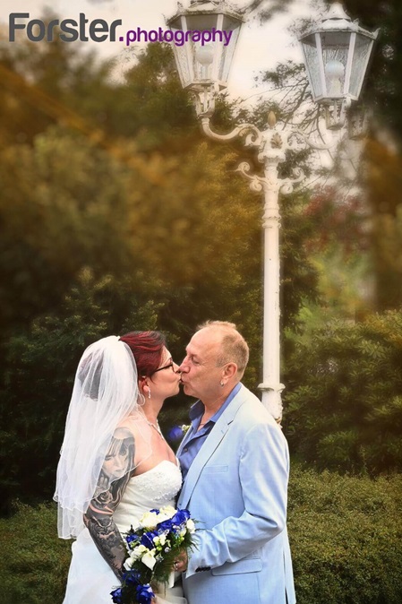 Ein Brautpaar im Hochzeits-Outfit beim Fotoshooting küsst sich innig unter einer Straßenlaterne