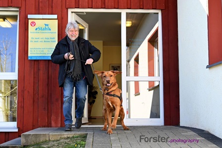 Mann mit Hund verlässt gut gelaunt eine Tierarzt-Praxis