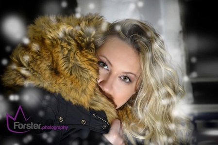 Junge Frau mit blonden Haaren trägt einen Wintermantel im Schneegestöber beim Style-Fotoshooting in Iserlohn und lächelt in die Kamera